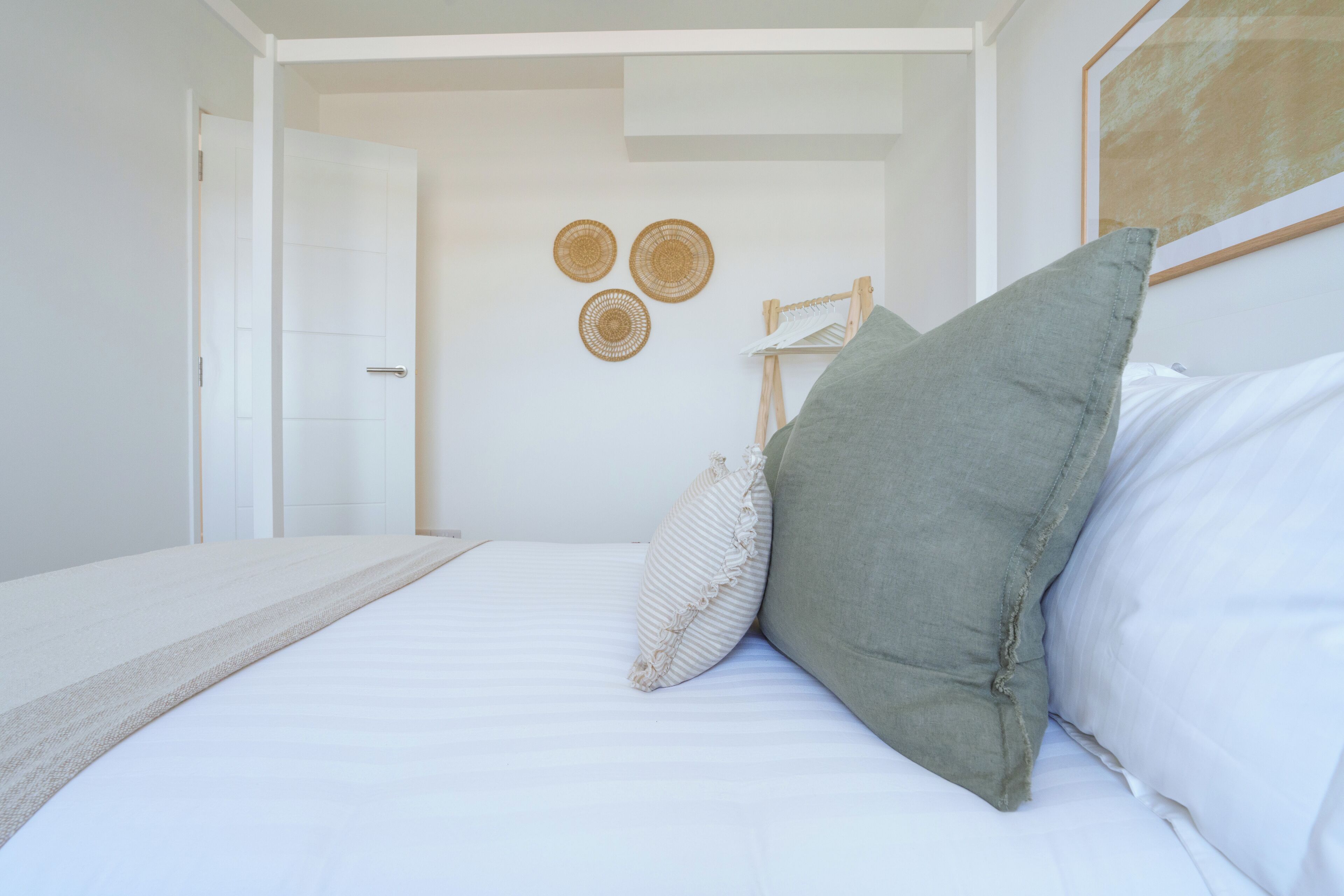 A bedroom with a bed, pillows, a door, and wall decorations.