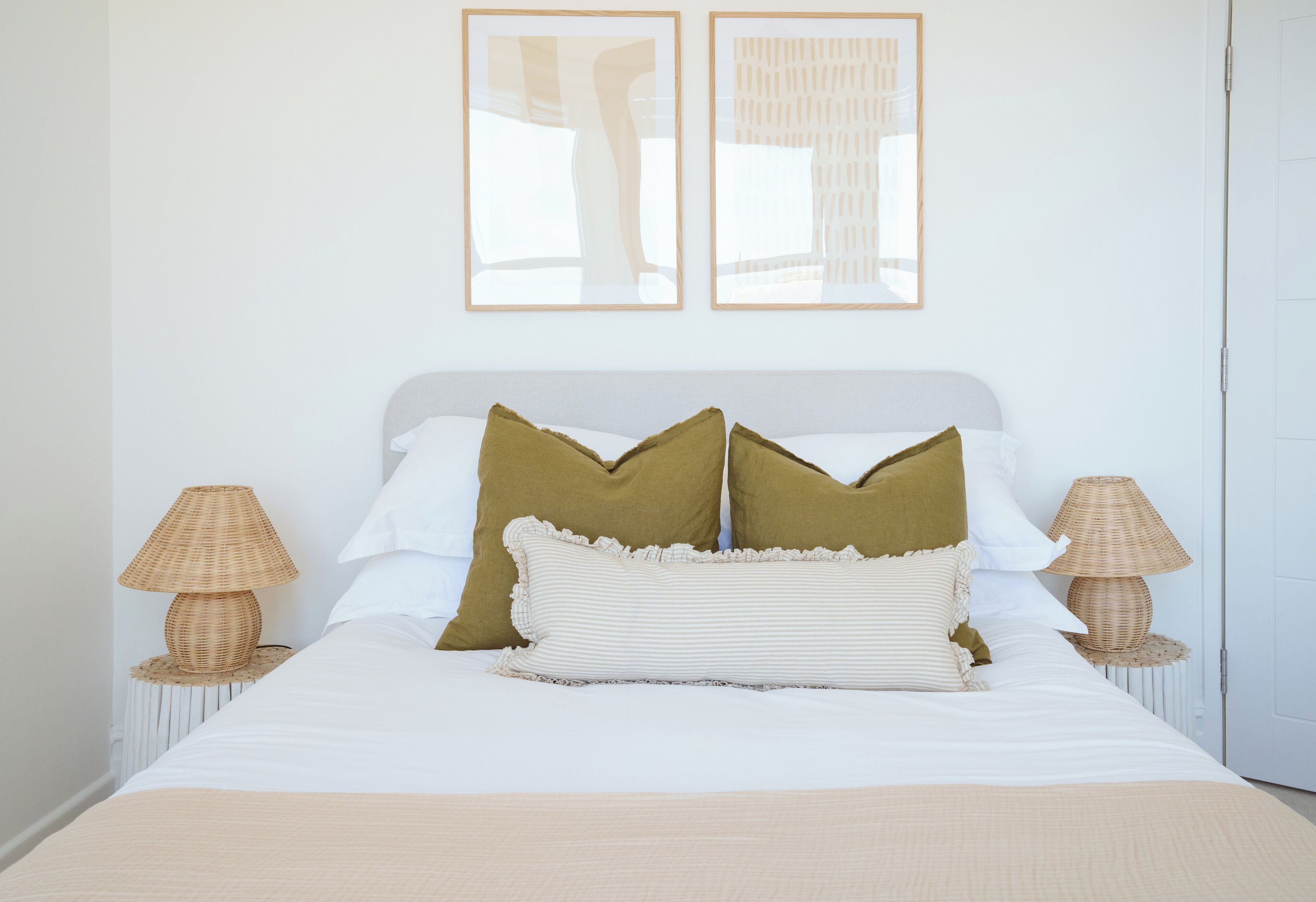 A neatly made bed with two pillows, a bedside lamp, and a framed picture on the wall.