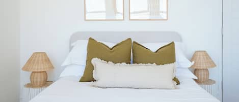 A neatly made bed with two pillows, a bedside lamp, and a framed picture on the wall.