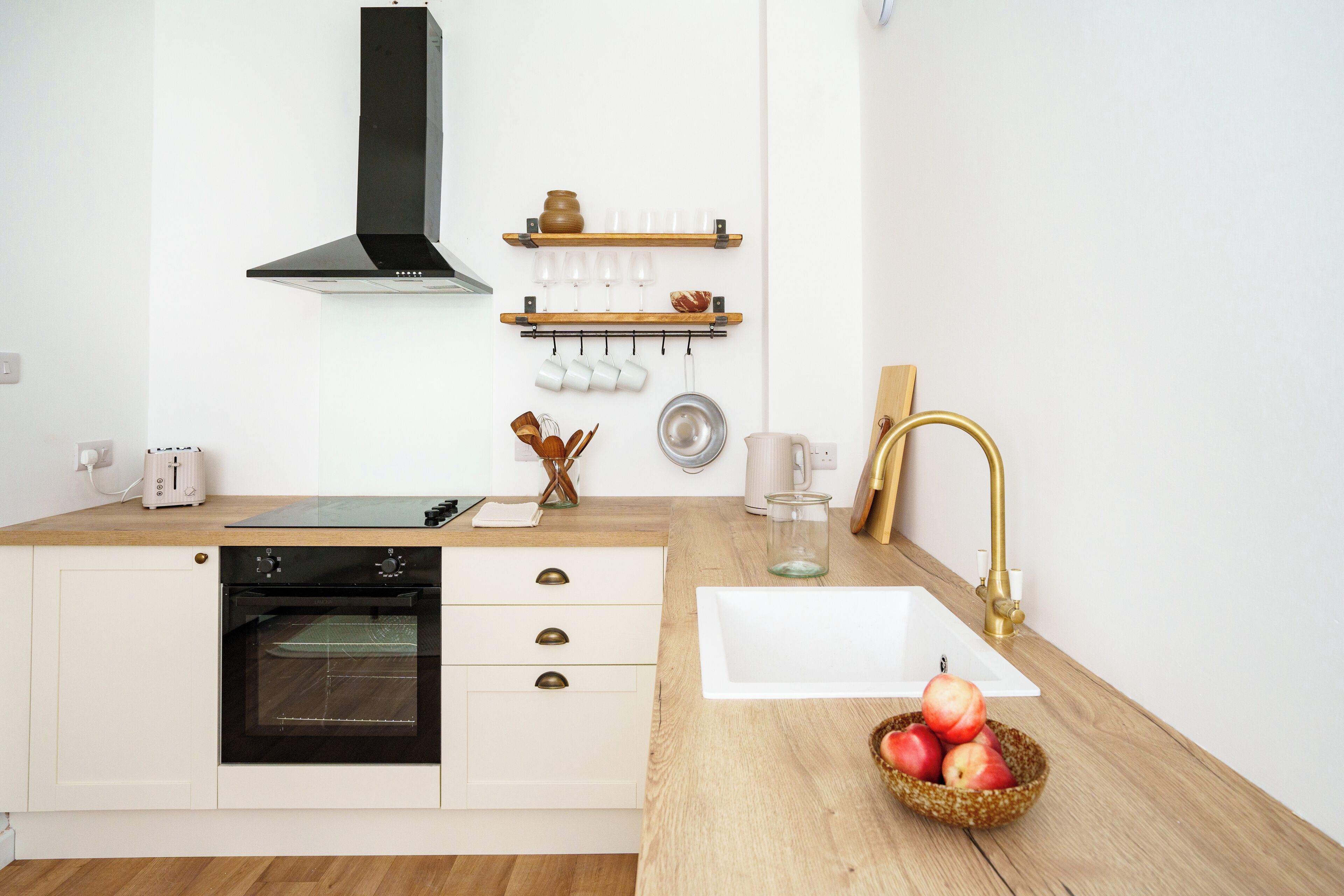 Une cuisine moderne dotée d’un four encastré, d’un évier blanc et d’un plan de travail en bois.