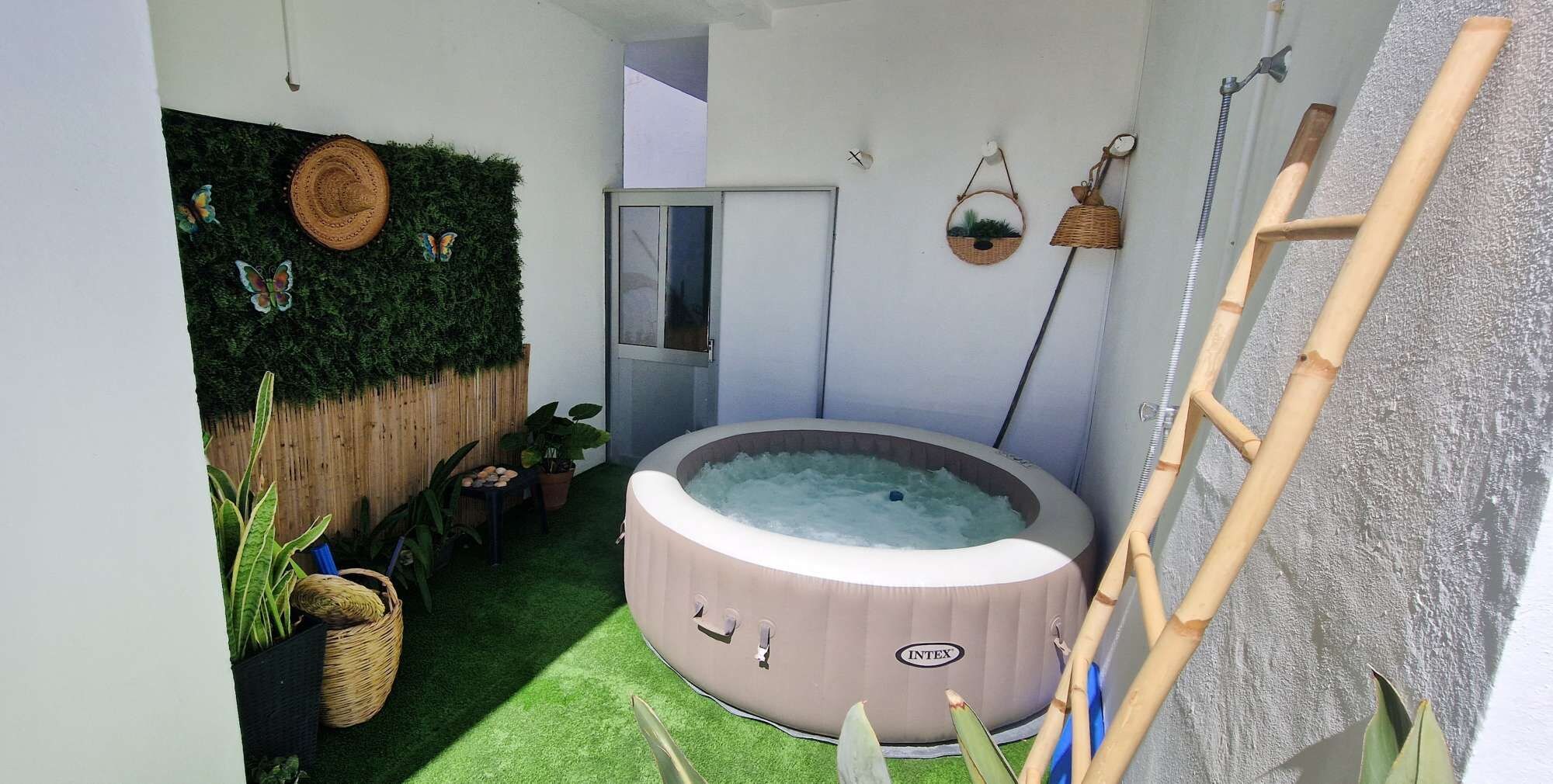 Un espace bien-être comprenant un jacuzzi, une échelle en bois et une horloge fixée au mur.