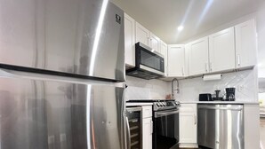A modern kitchen with stainless steel appliances, white cabinets, and a herringbone tile backsplash. - 4-bedroom apartment in the lower east side (New York)