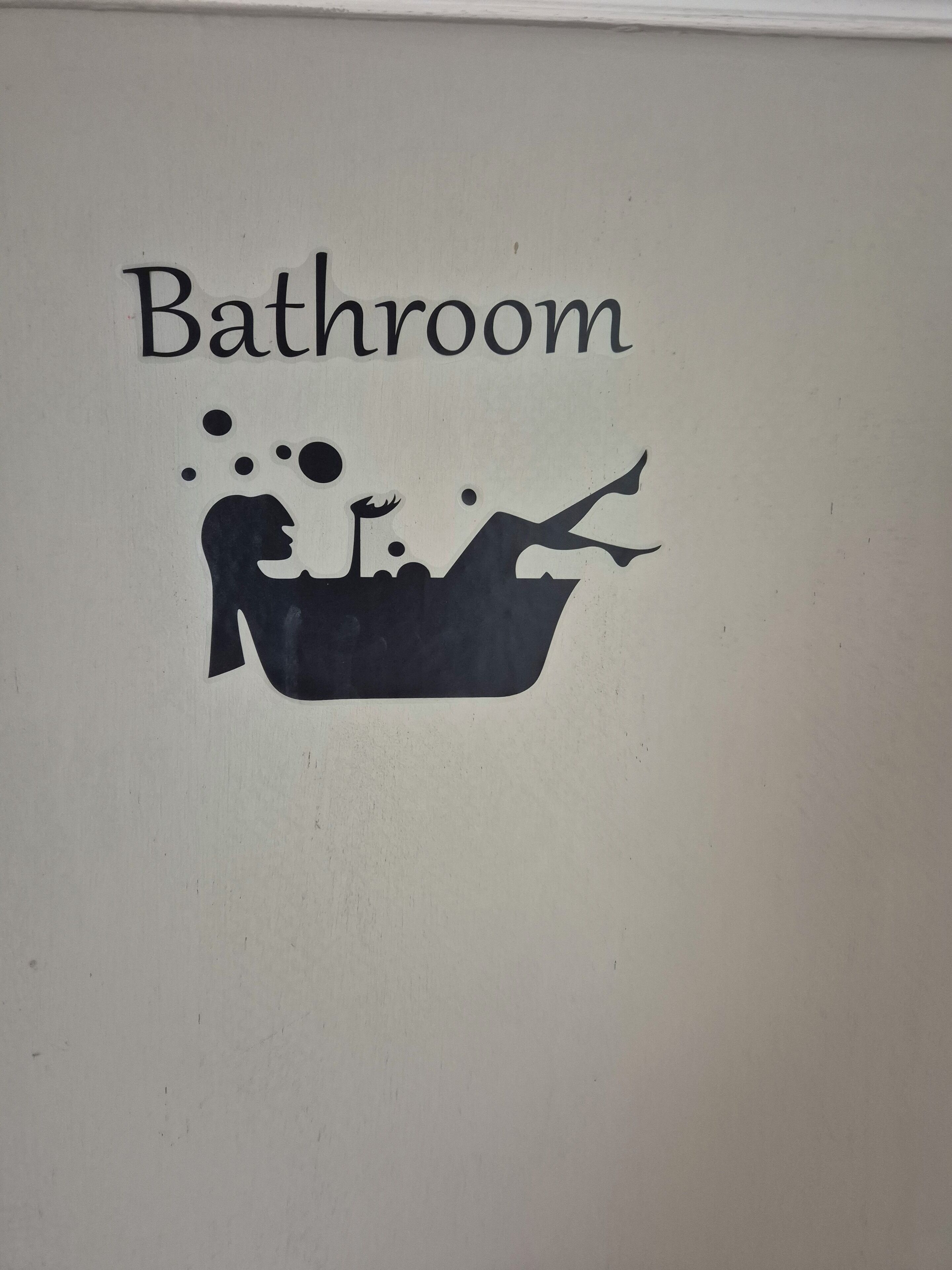 A bathroom sign with a silhouette of a person in a bathtub.