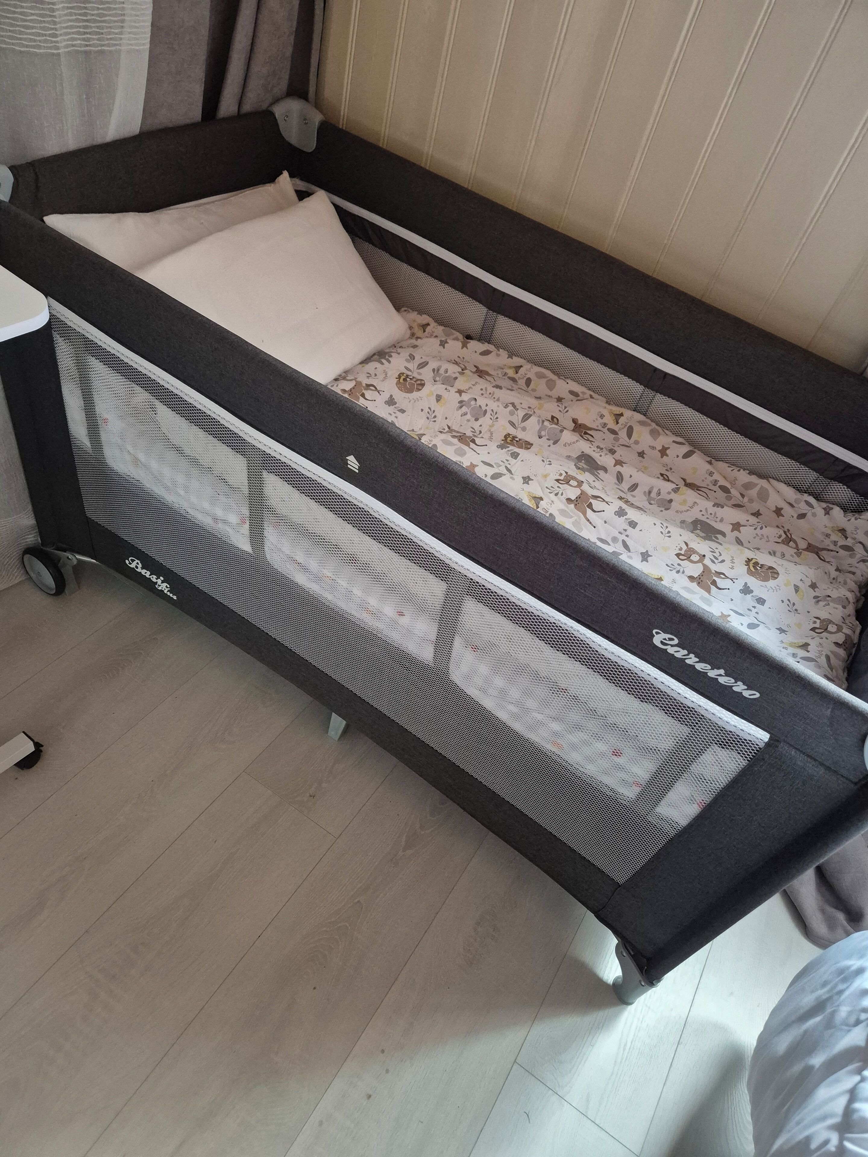 A convertible sofa bed with a mesh side panel and a patterned fabric cover.