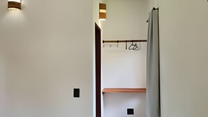 A narrow hallway with a wooden bench, a hanging coat rack, and a wall-mounted air conditioner. - Chalet 800 meters from Chapada dos Veadeiros Park, Wi-Fi (Alto Paraíso de Goiás)