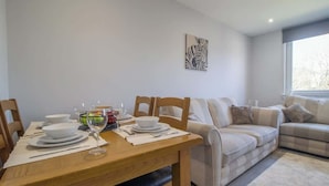 Un coin repas avec une table en bois dressée pour quatre personnes, un canapé et une œuvre d’art représentant un zèbre accrochée au mur.
