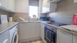 Une cuisine moderne équipée d’un lave-linge, d’un four à micro-ondes et d’une fenêtre offrant une belle vue.