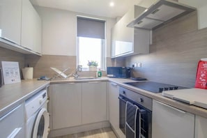 Uma cozinha moderna com máquina de lavar, micro-ondas e janela com vista.