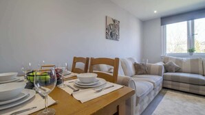 Un coin repas avec une table en bois dressée pour quatre personnes, un canapé et une œuvre d’art représentant un zèbre accrochée au mur.