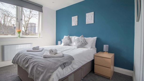 Une chambre à coucher avec un lit, une table de chevet et une fenêtre.