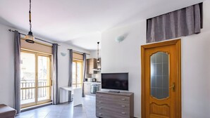 A modern living room with a TV, wooden cabinet, and a door with frosted glass. - Revolutionary Apartment near Duomo Station (Naples)