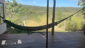 Una hamaca en una terraza de madera con vista a un promontorio boscoso.