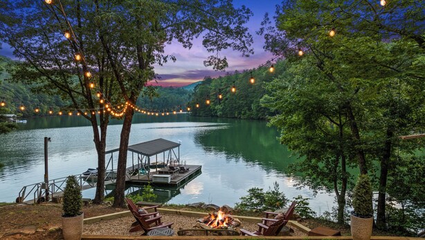 Une terrasse au bord du lac, avec un foyer, des sièges d’extérieur et des guirlandes lumineuses.