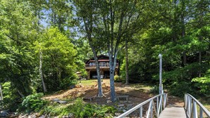 Une terrasse en bois mène à un chalet entouré d’une forêt dense.