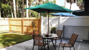 A patio with a round table, four chairs, and a green umbrella.