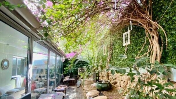 An outdoor patio with stone walls, a wooden deck, and a glass enclosure with tables and chairs. - VELO APPARTEMENT BABY FOOT 3 VRAIES CHAMBRES 1 MINUTES DE LA MER JARDIN VERANDA (Nice)