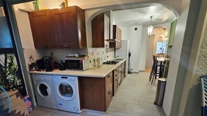 A compact kitchen with a washing machine, a microwave, and a coffee maker. - VELO APPARTEMENT BABY FOOT 3 VRAIES CHAMBRES 1 MINUTES DE LA MER JARDIN VERANDA (Nice)