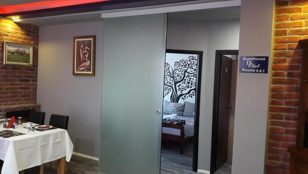 A hotel room with a bed, a nightstand, and a door leading to a guesthouse club area. - IN Club Hostel (Zagreb)
