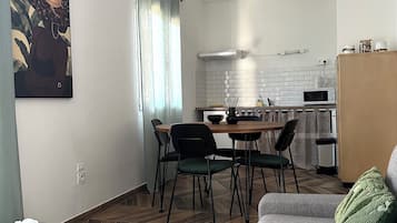 Un salon moderne comprenant un canapé, une table à manger avec des chaises, un coin cuisine avec un four à micro-ondes et un appareil de climatisation.