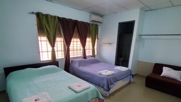 Habitación de hotel con dos camas, un sofá, una ventana con cortinas y un equipo de aire acondicionado.