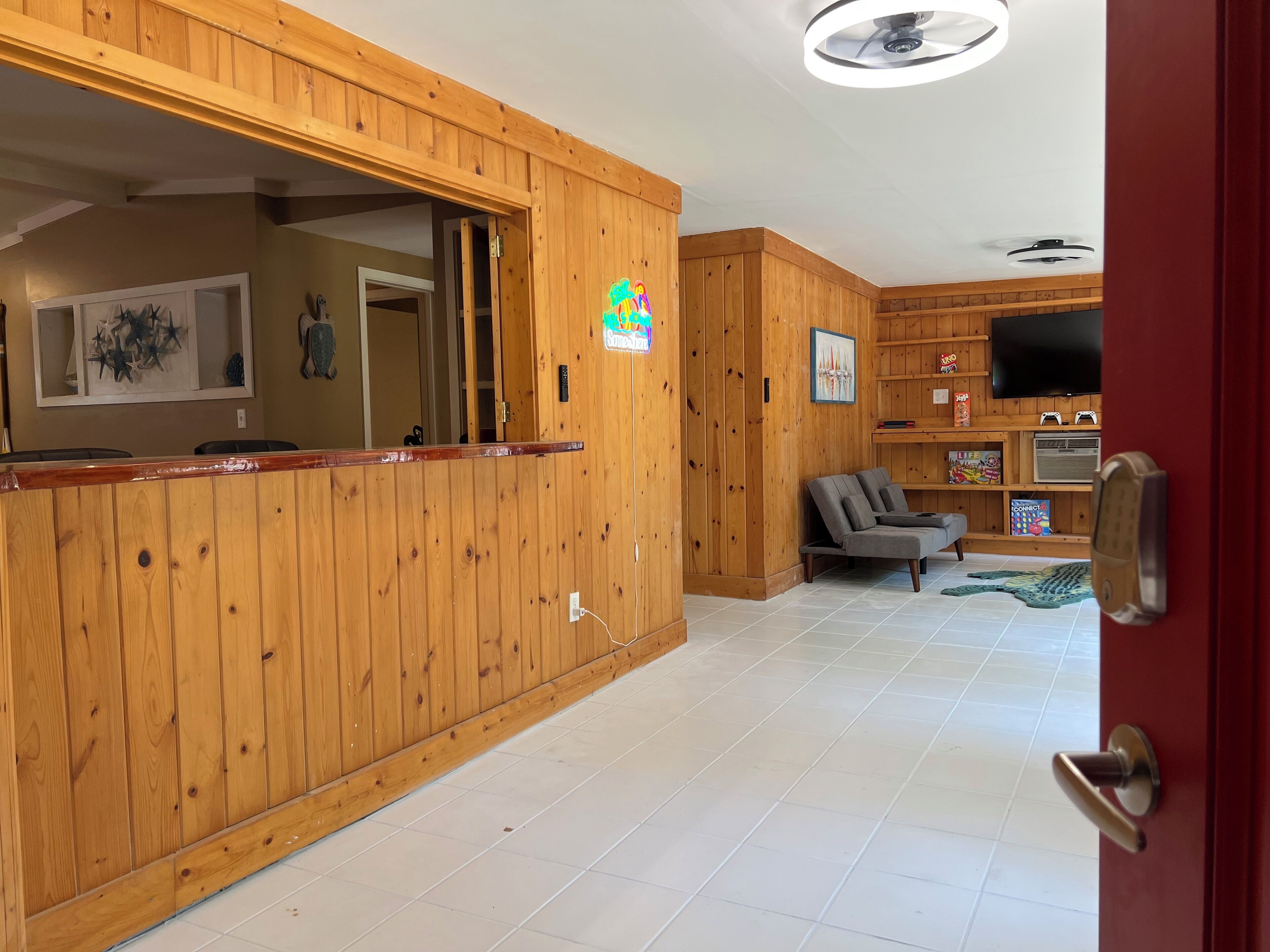 Un interior de madera con mostrador de recepción, un sofá gris y un televisor sobre una estantería.