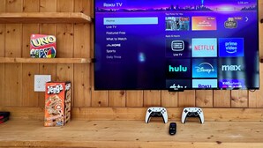 Un mur en bois sur lequel est fixée une télévision affichant l’interface Roku, ainsi que des manettes de jeu et des en-cas.