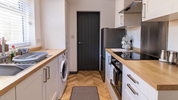A compact kitchen with a washing machine, a refrigerator, and a microwave.