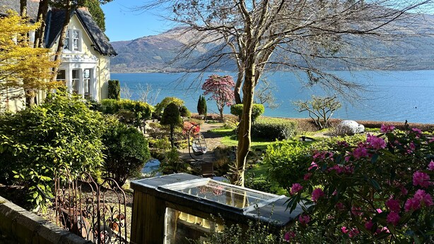 A lakeside property with a house, garden, and a view of the lake and mountains. - Camus House (Onich)