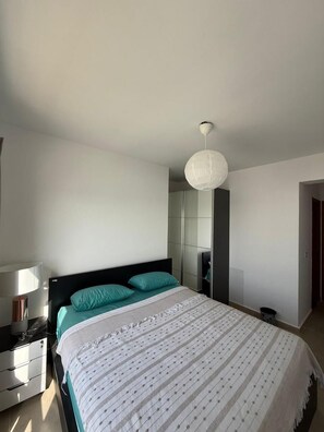 Een slaapkamer met een bed, een nachtkastje, een lamp en een hanglamp.