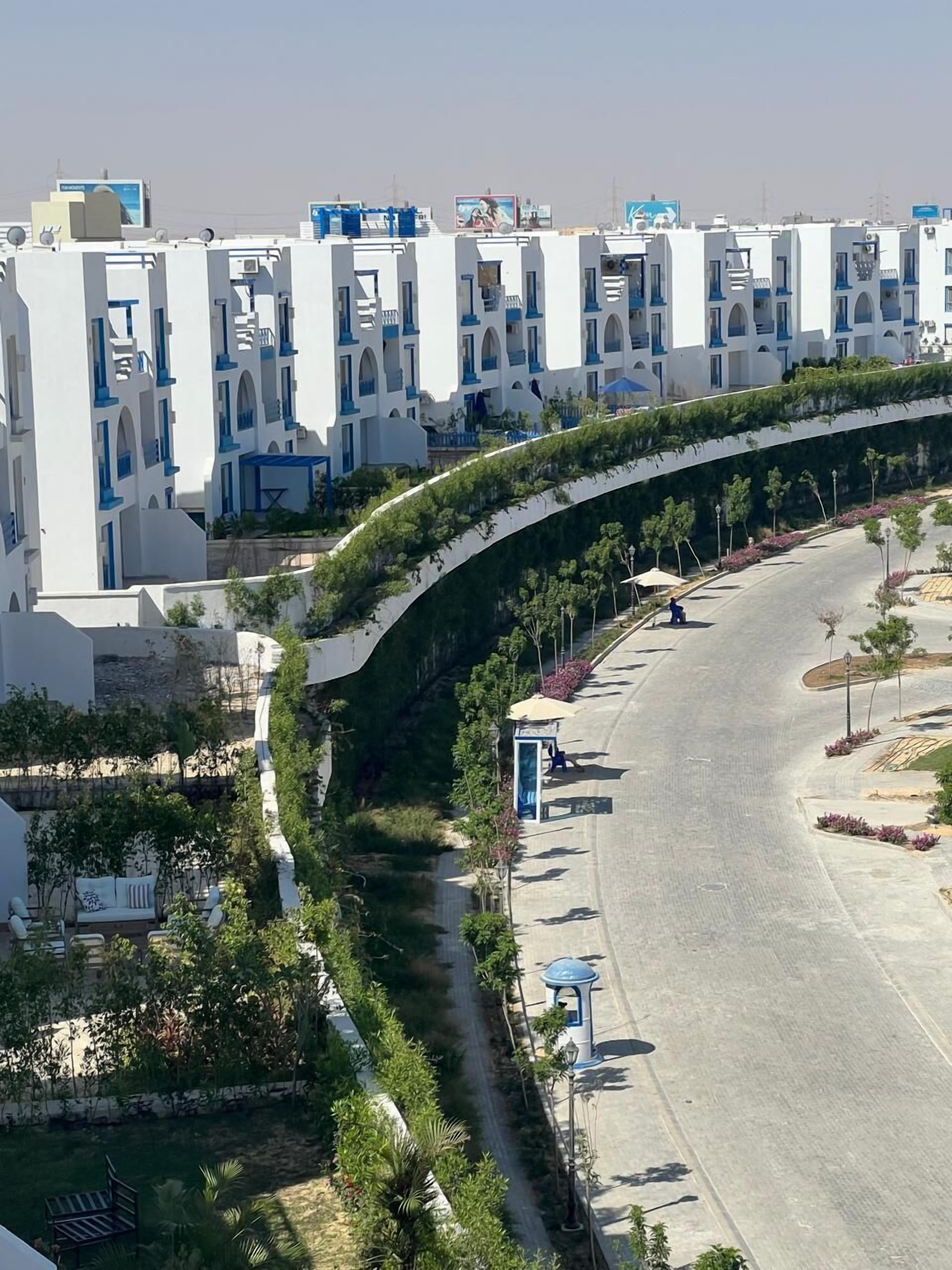 A modern hotel with a curved pathway, outdoor seating, and a clear view of the street.