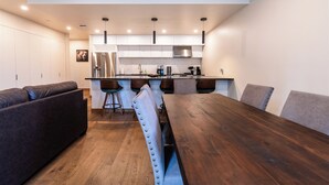 Una cocina moderna con una mesa de comedor de madera, taburetes de bar y un banco empotrado.