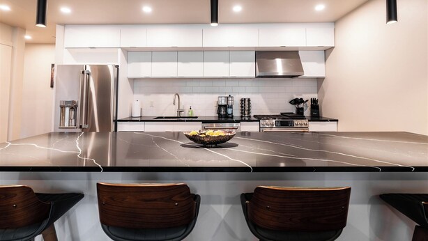 Una cocina moderna con una isla grande, electrodomésticos de acero inoxidable y asientos de bar.