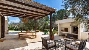 Un patio al aire libre con mobiliario de mimbre, una pérgola y piso de piedra.