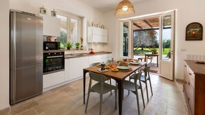 Una cocina moderna con comedor, electrodomésticos de acero inoxidable y vistas al jardín.
