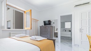Una habitación de hotel con cama, cómoda, espejo y puerta al baño.