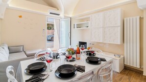 A modern dining area with a white table set for four, clear chairs, and a white cabinet with decorative panels. - Casa Margot by BarbarHouse (Campomarino)