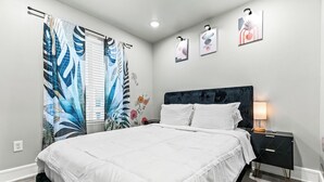 Une chambre à coucher avec un lit, une table de chevet et une fenêtre avec des rideaux.