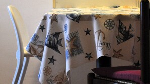 A dining area with a table covered by a nautical-themed tablecloth, a white chair, and a dark chair with a purple cushion. - Relaxation a stone's throw from the sea. [Terrace] [Garage] (Zoagli)