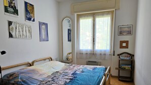 A bedroom with a bed, a mirror, a window with curtains, and a small shelf with items. - Relaxation a stone's throw from the sea. [Terrace] [Garage] (Zoagli)