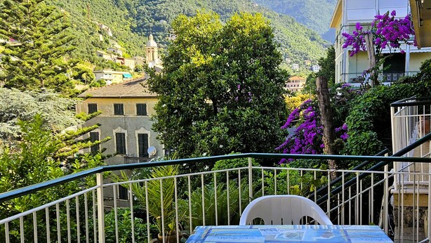 A balcony with a table and chairs, overlooking a mountainous landscape with buildings and greenery. - Relaxation a stone's throw from the sea. [Terrace] [Garage] (Zoagli)