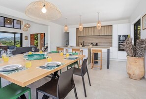 A modern kitchen with wooden cabinets, a central island, and pendant lighting. - Villa LALALAND  (Le François)