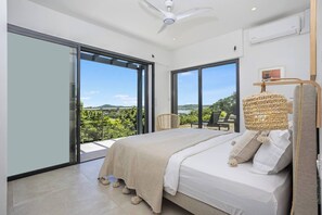 A bedroom with a large bed, a ceiling fan, and a view of the outdoors. - Villa LALALAND  (Le François)