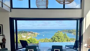 Ein modernes Wohnzimmer mit Blick auf das Meer und viel Grün.