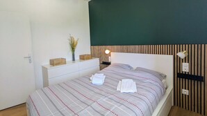 Een moderne slaapkamer met een bed, nachtkastje, lamp en een wandlamp.