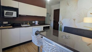 Een moderne keuken met een magnetron, koffiezetapparaat en wasmachine.