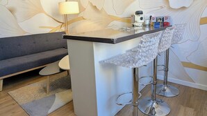 Een moderne barruimte met een minimalistisch design, met een bargedeelte, twee barkrukken en een lamp.