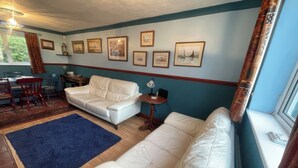A living room with a white sofa, a blue rug, and framed pictures on the wall. - 11 Penygroes (Holyhead)