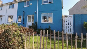 A two-story residential building with a blue exterior and white windows. - 11 Penygroes (Holyhead)