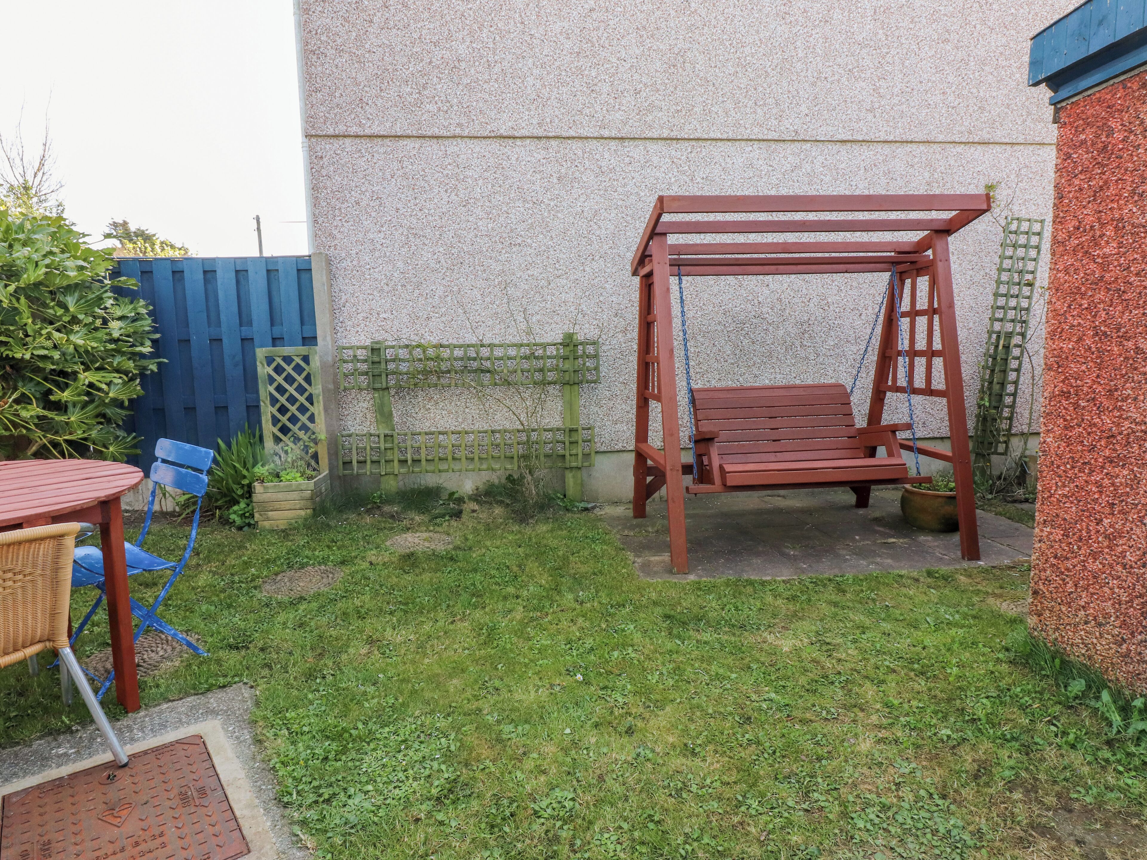 A patio area with a swing set, a table with chairs, and a small garden.