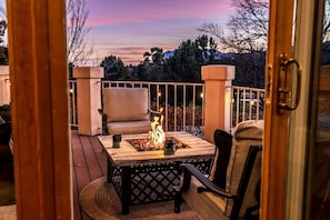 Eine Terrasse mit Feuerstelle, Stühlen und Blick auf die Landschaft.